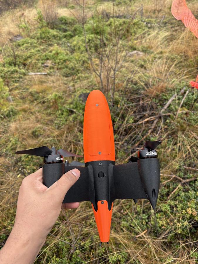 The orange streamlined BatDrone held in one hand